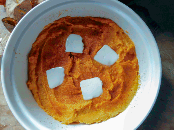 Mashed Sweet potatoes in round casserole dish with butter squares on top