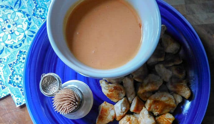 Firecracker Chicken Bites on a blue dish with dipping sauce in white bowl