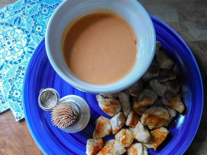 Firecracker Chicken Bites on a blue dish with dipping sauce in white bowl