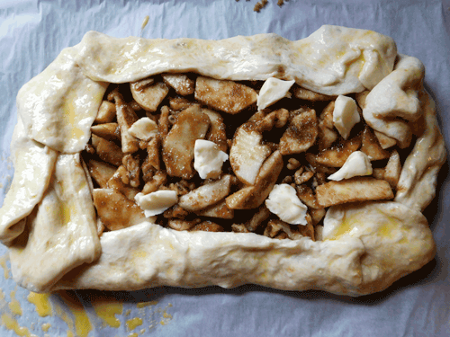 Apples coated with cinnamon and sugar in a square free form pie on a baking sheet for Apple Galette