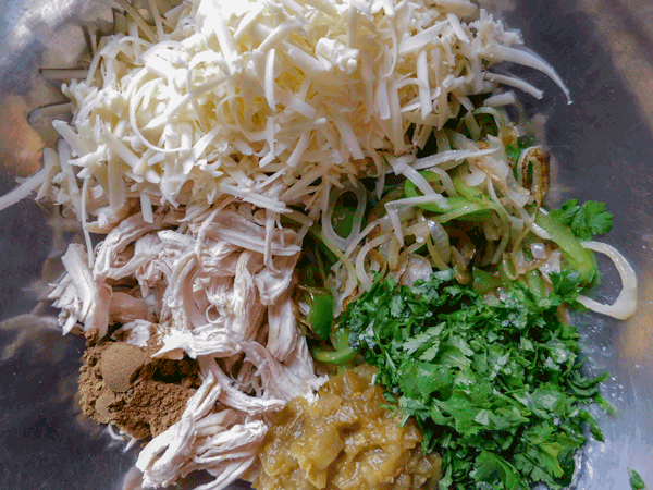 Shredded cheese chicken, chiles, peppers, onion and cilantro in silver bowl