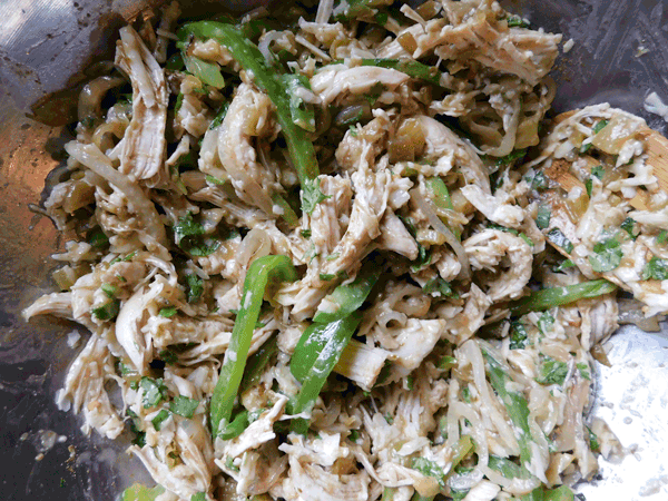 Shredded chicken cheese peppers onions and chiles mixed toether ready for Chicken Enchiladas Suizas