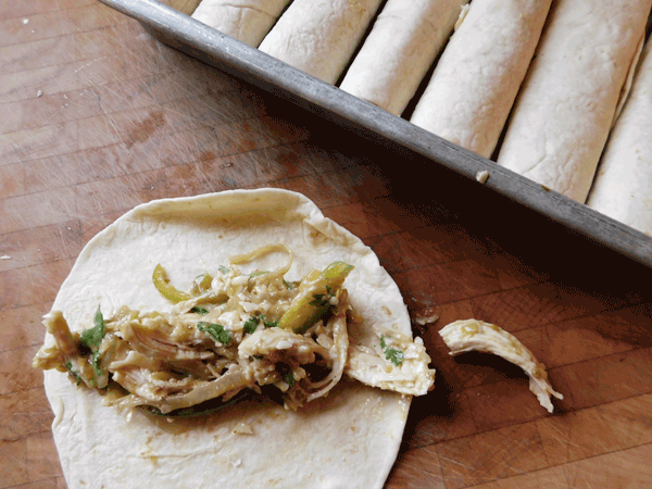 chicken mixture on flour tortilla on chopping block