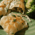 Crispy chicken enchiladas suizas on a green plate with broccoli