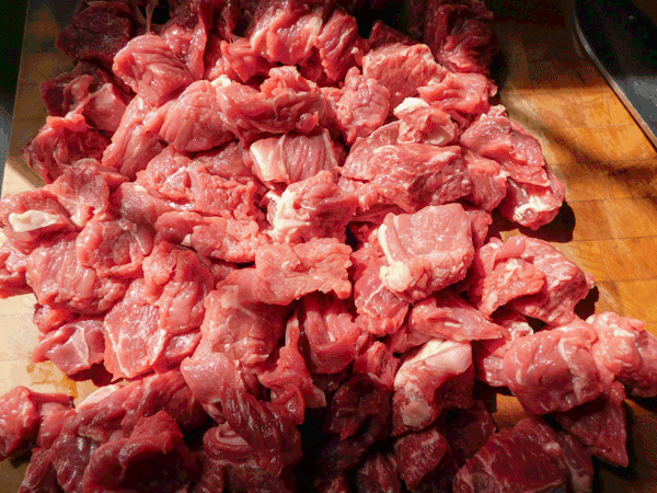 Cubed Beef Chuck roast on chopping block