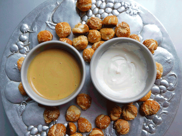 Soft pretzel bites on a silver platter with honey mustard and horsradish dipping sauce in white bowls