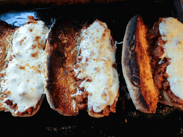 Cooked Sausage in tomato sauce on toasted hoagie buns with cheese