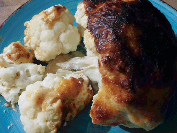 cauliflower with a cooked cheesy topping on a blue plate