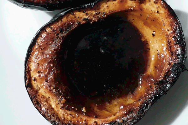 Close up of one side of an acorn squash roasted with brown sugar syrup in the middle