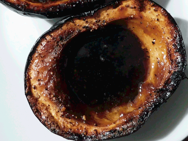Close up of one side of an acorn squash roasted with brown sugar syrup in the middle