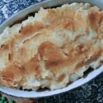 Browned Potatoes in a white oval casserole dish on black and white placemat