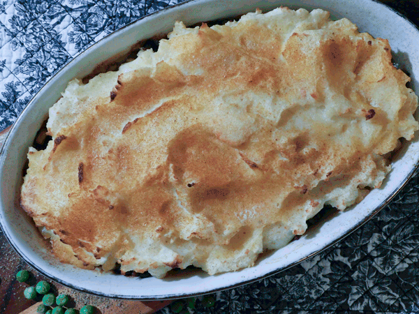 Browned Potatoes in a white oval casserole dish on black and white placemat