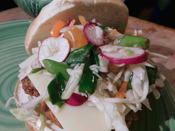 Fried chicken with colesalw on a white bun on a green plate