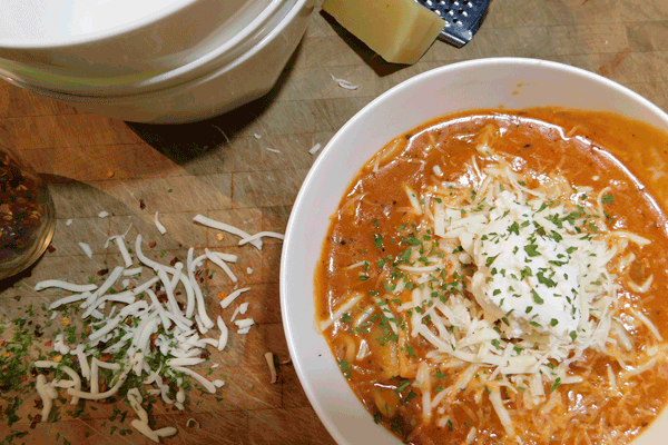 Bowl of soup on chopping block with cheese