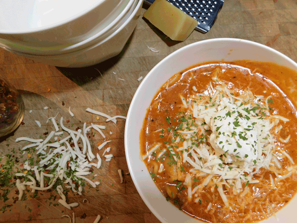 Bowl of soup on chopping block with cheese