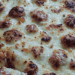 Closeup of cooked cheese covered meatballs