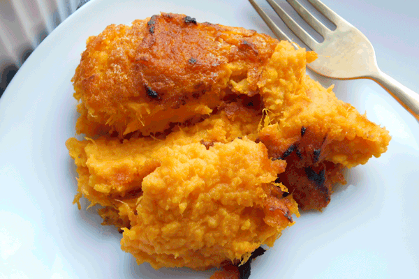 Mashed crispy sweet potatoes on a white plate with a fork
