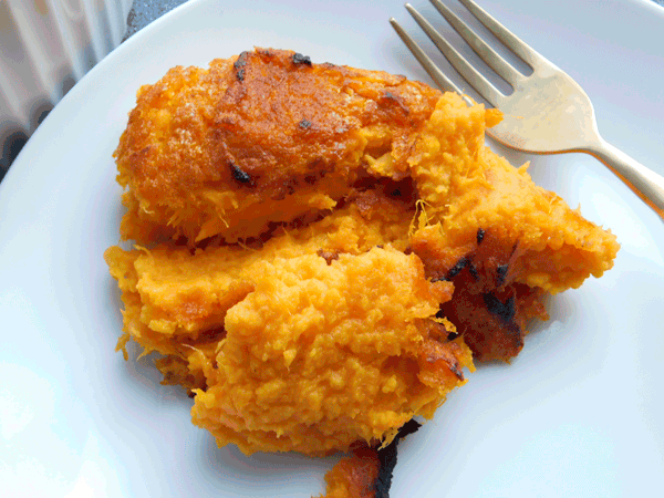 Mashed crispy sweet potatoes on a white plate with a fork