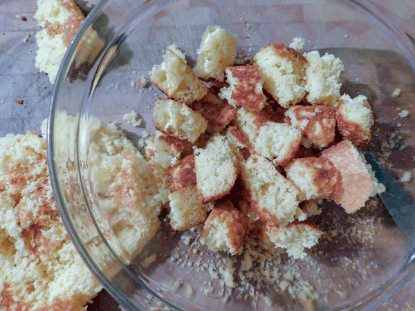 Cornbread cut in pieces ready to be dressed in a glass bowl