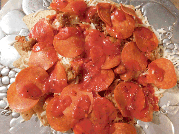 Chips with pepperoni and cheese on silver platter