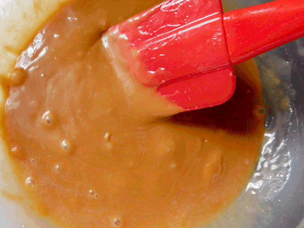 Melted caramel in a glass bowl with a red spatula