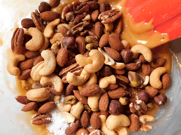 Melted caramel with mixed nuts on top in glass bowl