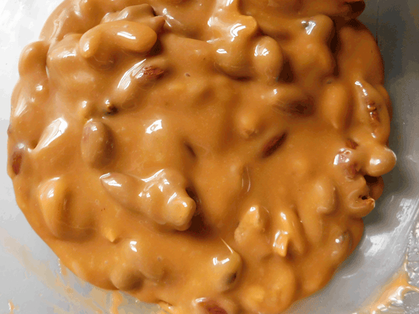 Nuts and caramel mixed together in glass bowl