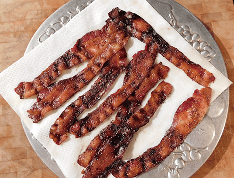 Crispy cooked bacon on paper towels on silver platter