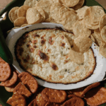 Cooked Cheddar Jalapeno Dip in casserole with chips and crackers around it