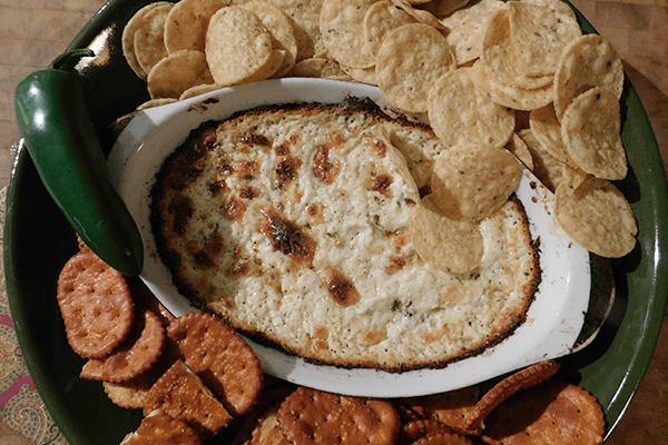 Cooked Cheddar Jalapeno Dip in casserole with chips and crackers around it