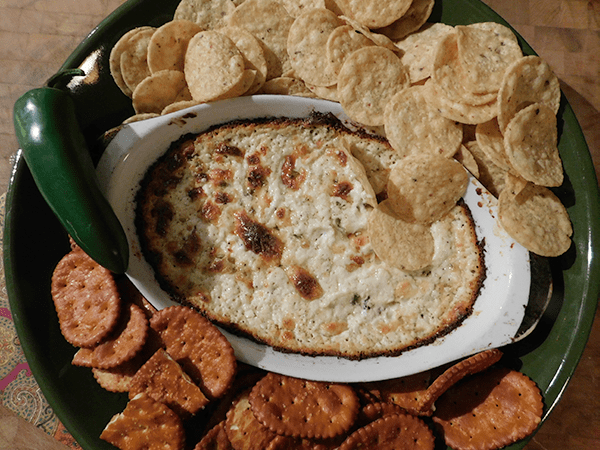 Cooked Cheddar Jalapeno Dip in casserole with chips and crackers around it