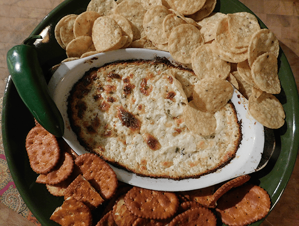 Cooked Cheddar Jalapeno Dip in casserole with chips and crackers around it