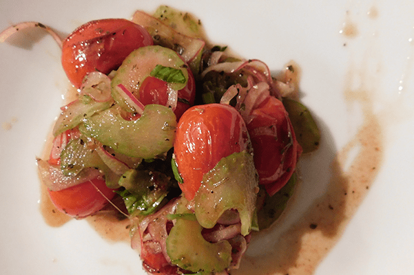 Charreed grape tomatoes, red onion and celery on a white plate