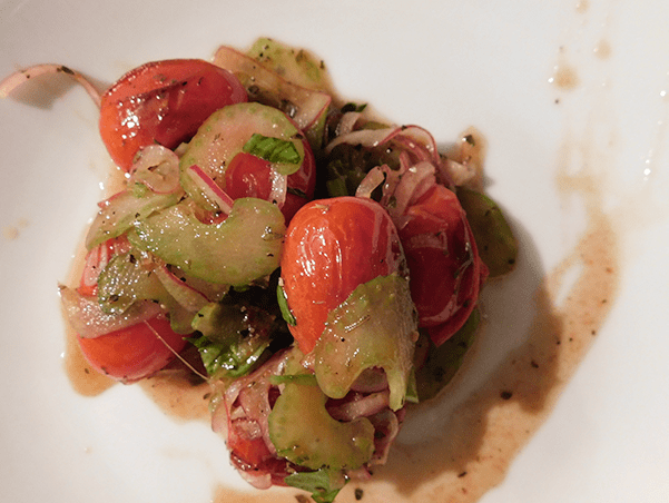 Charreed grape tomatoes, red onion and celery on a white plate