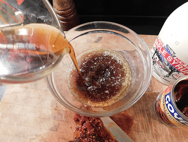 Maple syrup being poured into bowl with syrup and chipotles next to it