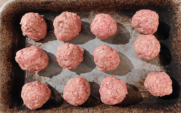 Raw small meatballs on a baking tray