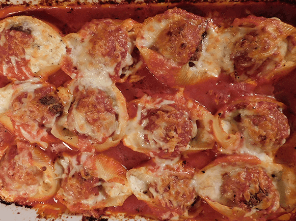 Meatball stuffed shells in casserole on top of tomato sauce and cooked