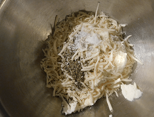 Ricotta cheese, mozzarella, parmesan and salt & pepper in silver mixing bowl