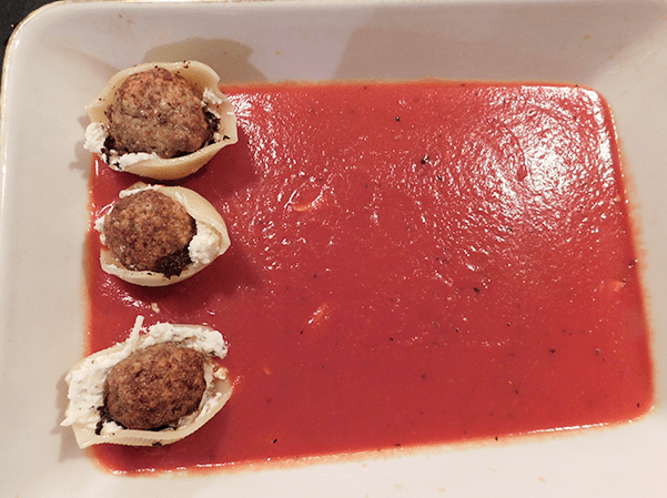 Meatball stuffed shells in casserole on top of tomato sauce