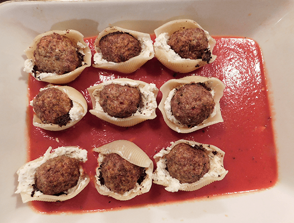 Meatball stuffed shells in casserole on top of tomato sauce