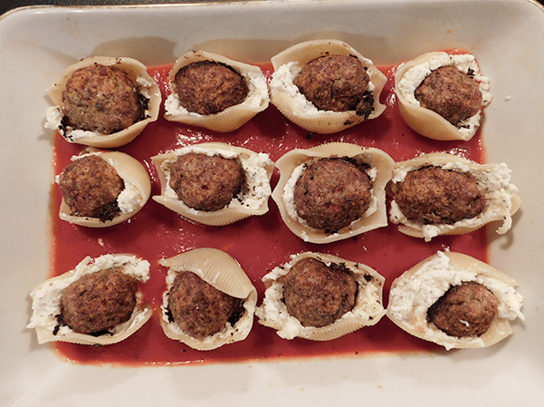 Meatball stuffed shells in casserole on top of tomato sauce