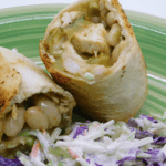 Baked chicken chimichanga cut in half on a plate with coleslaw