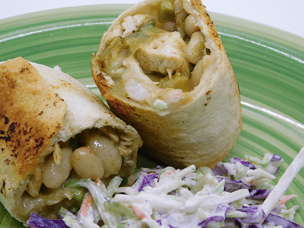Baked chicken chimichanga cut in half on a plate with coleslaw