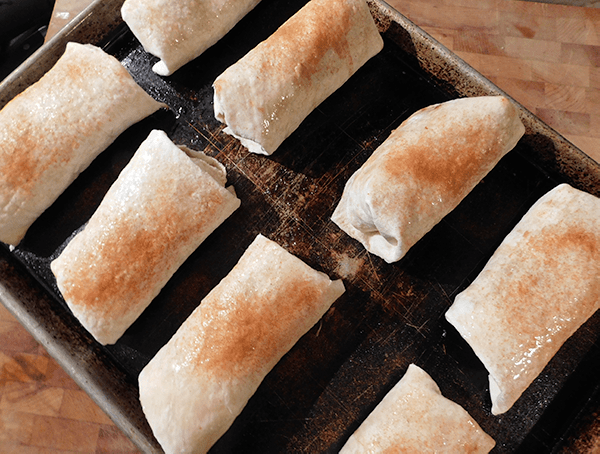 Rolled chicken chimichangas on a cooking sheet