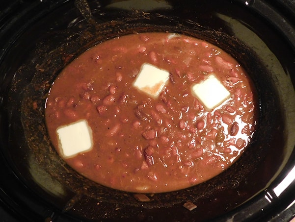 Cooked red beans in crockpot with 3 pats of butter floating on top