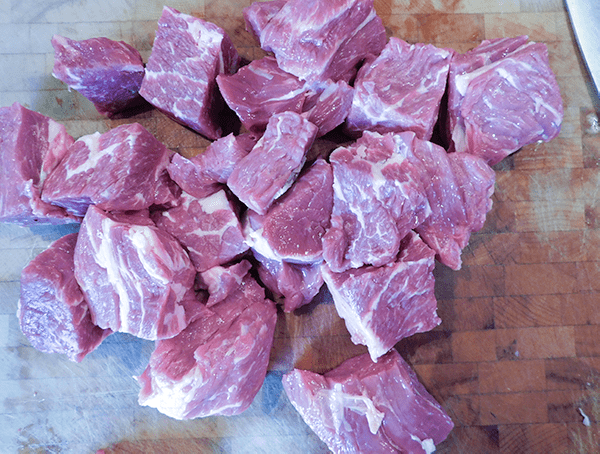 Beef chuck roast cut into 2" pieces on chopping block