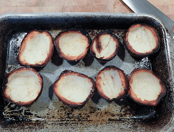 Cooked and crispy potato skins on a baking sheet on a chopping block