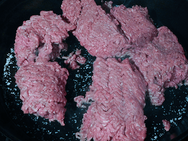 Ground beef in cast iron skillet over salt