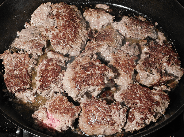 Cooking beef in skillet with a few pink areas still showing
