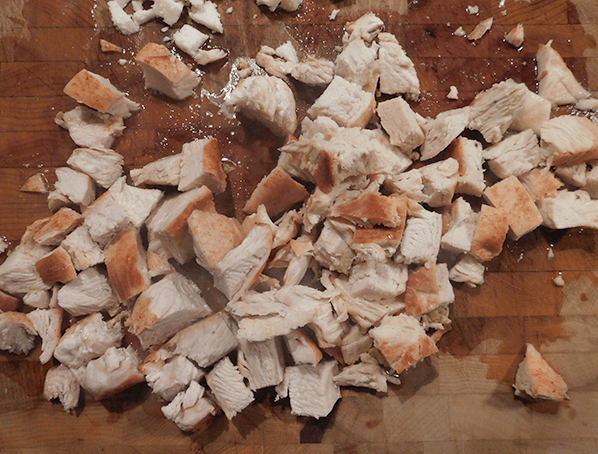 Baked chicken, chopped on a cutting board, ready for sauce before going on Buffalo Chicken Nachos